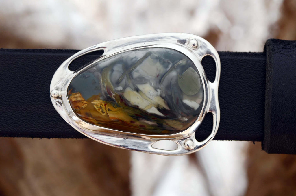Silver belt buckle with dramatic morisonite jasper stone. Stone colors are deep blue-grays mixed with orange, red and cream colors.